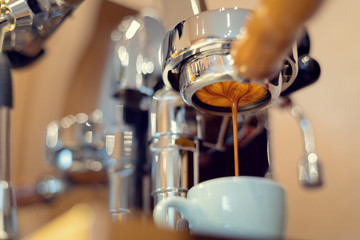 A coffee machine is preparing a cup of espresso. Blurred background.