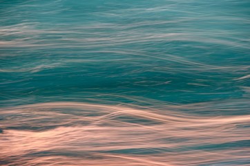 Abstract dynamic, dark turquoise and glowing sunset, background in the form of wavy stripes of lines.