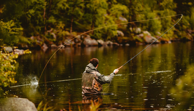 Fisherman using rod fly fishing in mountain river