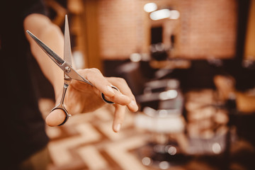Barber hairdresser holds scissors on background chair, beauty salon for men