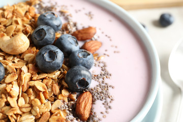 Bowl of tasty oatmeal with blueberries and yogurt on table, closeup