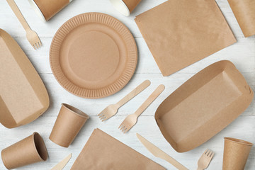 Flat lay composition with new paper dishware on white wooden background. Eco life