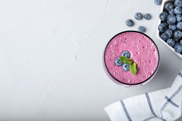 Flat lay composition with glass of tasty blueberry smoothie on grey table. Space for text