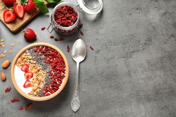 Flat lay composition of smoothie bowl with goji berries on grey table. Space for text