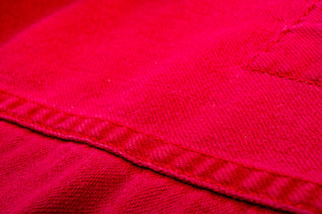 clothing items stonewashed red cotton fabric texture with seams, clasps, buttons and rivets, macro