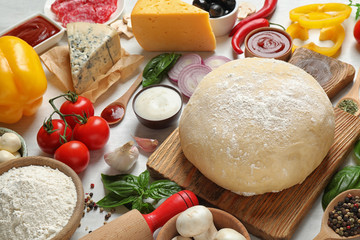 Fresh dough and ingredients for pizza on white table