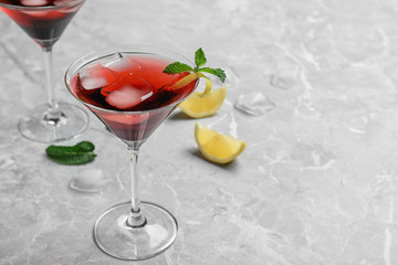 Glass of delicious cocktail with ice on light grey table. Space for text