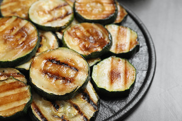 Delicious grilled zucchini slices served on grey table, closeup