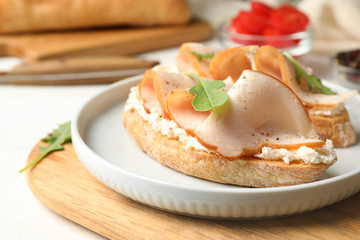 Board with plate of delicious chicken bruschettas on table, closeup