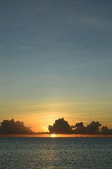 Fototapeta na wymiar オレンジ色の夕日が水平線に落ちる穏やかな海
