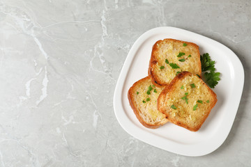 Slices of toasted bread with garlic and herb on light grey marble table, top view. Space for text