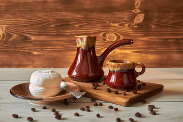 cup of coffee with cezve and marshmallow on a wooden table