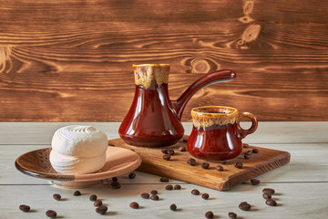 cup of coffee with cezve and marshmallow on a wooden table