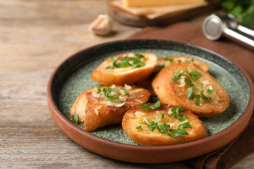 Slices of toasted bread with garlic, cheese and herbs on wooden table