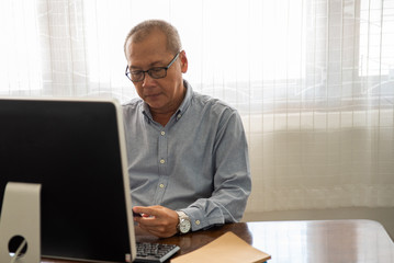 Senior man shopping online using computer and credit card.