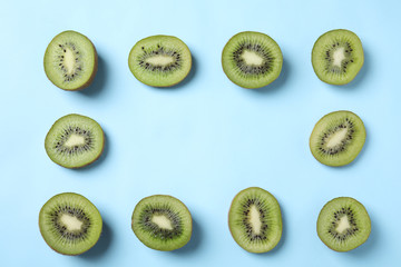 Fototapeta premium Frame made of fresh kiwis on light blue background, top view. Space for text