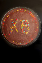 Chocolate cake at Easter with inscription of HV with colored sprinkles.