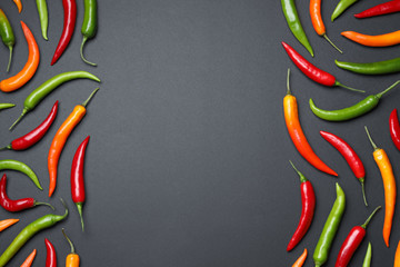 Frame made with different chili peppers on black background, flat lay. Space for text