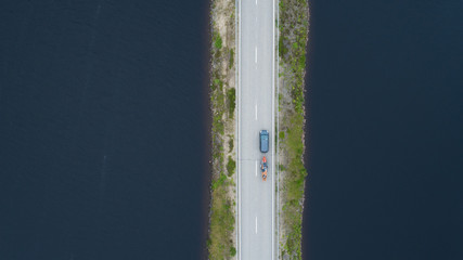 View from above on the road going along the blue river. Car moving on road. Summer photography with bird's eye view
