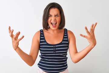 Young beautiful woman wearing blue striped t-shirt standing over isolated white background shouting with crazy expression doing rock symbol with hands up. Music star. Heavy concept.