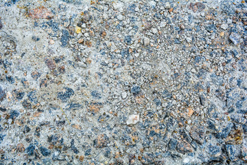 Ground street surface of broken asphalt or cement with pothole and stone pebbles