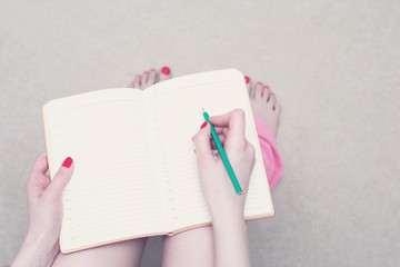 Girl sitting on toilet, woman writes in her notebook, closeup, copy space, advertising, slogan, top view, toned