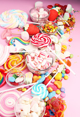 candies with jelly and sugar. colorful array of different childs sweets and treats on pink