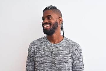 Obraz premium African american man with braids wearing grey sweater over isolated white background looking away to side with smile on face, natural expression. Laughing confident.