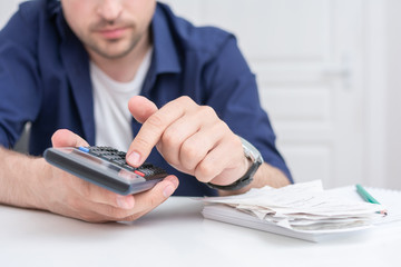Man calculates budget, bills and calculator, men's hands, cropped image, close up, toned