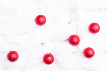 Red Christmas toys on a background of white snow made of cotton, copy space, for advertising, close up