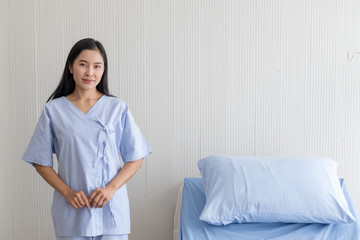 Asian girl patient standing beside bed in hospital