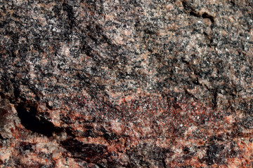 Abstract blurred natural background. Black with pink-orange rough surface of granite. Design and construction concept.