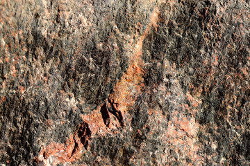 Abstract blurred natural background. Black with pink-orange rough surface of granite. Design and construction concept.