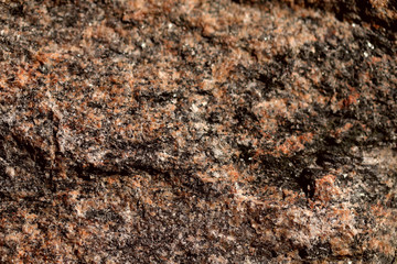 Abstract blurred natural background. Black with pink-orange rough surface of granite. Design and construction concept.