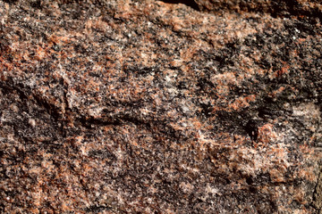 Abstract blurred natural background. Black with pink-orange rough surface of granite. Design and construction concept.