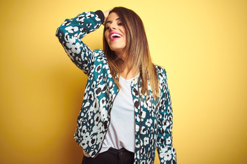 Young beautiful woman wearing casual jacket over yellow isolated background smiling confident touching hair with hand up gesture, posing attractive and fashionable