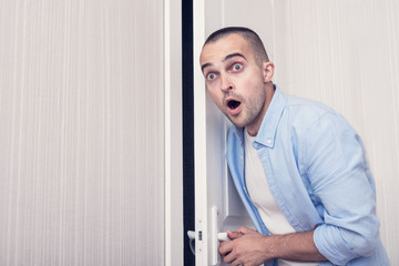 Fototapeta premium Shocked, stunned guy eavesdropper at the door, portrait, toned