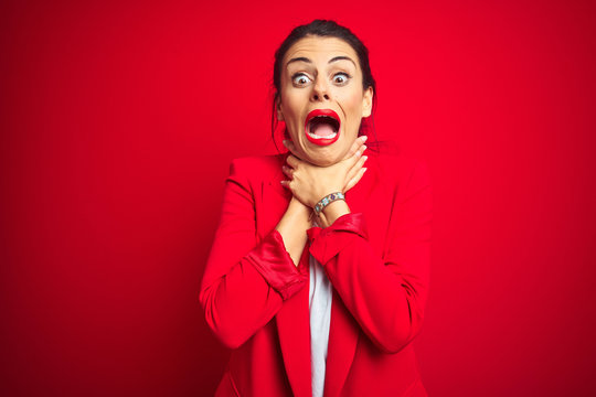 Young beautiful business woman standing over red isolated background shouting suffocate because painful strangle. Health problem. Asphyxiate and suicide concept.