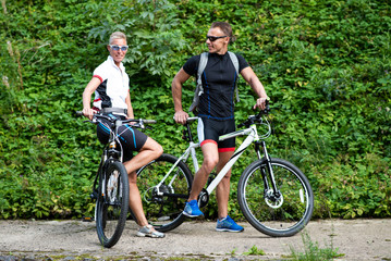 Obraz premium Man and woman with bicycles posing in the park.