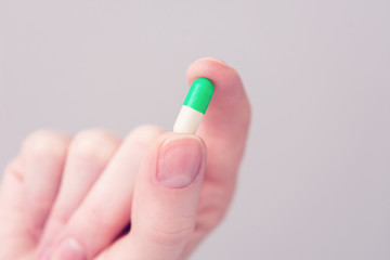 Person holding green capsule, woman's hand, closeup, cropped image, copy space