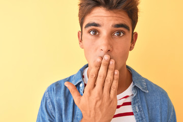 Young handsome man wearing striped t-shirt and denim shirt over isolated yellow background cover...