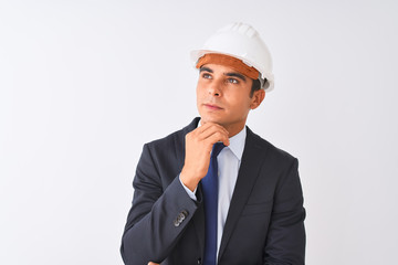 Young handsome architect man wearing suit and helmet over isolated white background with hand on chin thinking about question, pensive expression. Smiling with thoughtful face. Doubt concept.