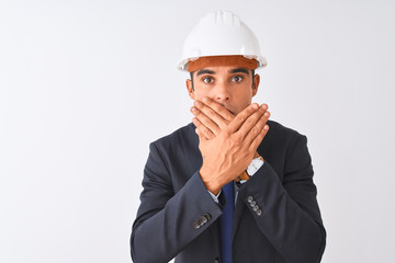 Young handsome architect man wearing suit and helmet over isolated white background shocked covering mouth with hands for mistake. Secret concept.