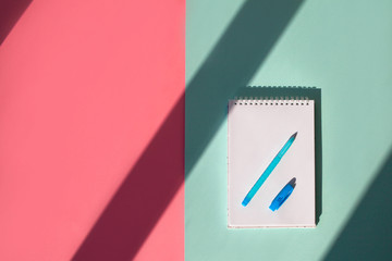 Spiral notebook with handle on blue background, pink background copy space. Top view, with shadow.