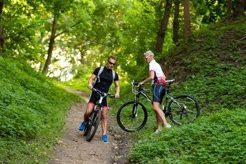 Fototapeta premium A man and a woman on bicycles go down the hill.