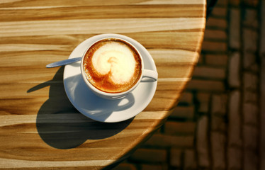 Cup of hot cappucino on the wooden table. Early morning breakfast