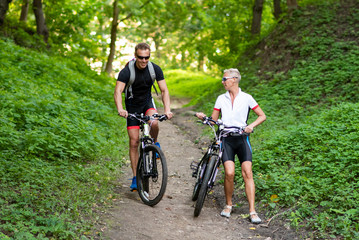 Obraz premium A man and a woman on bicycles go down the hill.