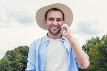 Attractive cowboy talking on the phone, happy man in hat smiling, portrait, toned