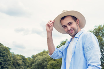 Attractive man in hat outdoors, happy man smiling at camera, portrait, copy space, toned