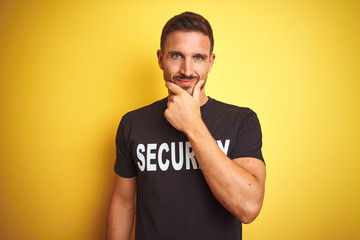 Young safeguard man wearing security uniform over yellow isolated background looking confident at...